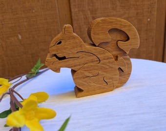 May include: A wooden squirrel puzzle toy with intricate cutouts. The squirrel is holding a nut in its paws and has a bushy tail.