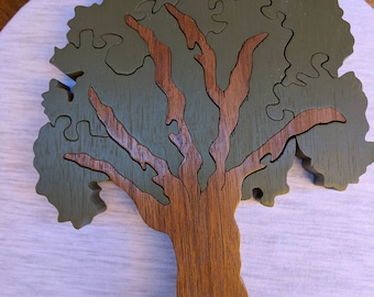 May include: A wooden tree puzzle with a brown trunk and green leaves. The puzzle is made of multiple pieces that fit together to form the shape of a tree.