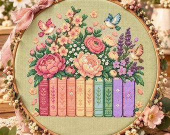 Può includere: Un telaio da ricamo circolare in legno contenente un motivo a punto croce di una fila di libri colorati sormontati da una vivace composizione floreale. Due piccoli uccelli sono ricamati sopra i fiori su un tessuto verde chiaro.