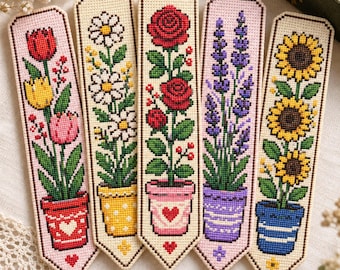 Può includere: Cinque segnalibri rettangolari a punto croce con disegni floreali verticali in vaso. I motivi includono tulipani in un vaso rosso, margherite in uno giallo, rose in uno rosa, lavanda in uno viola e girasoli in uno blu, su tessuto color crema.
