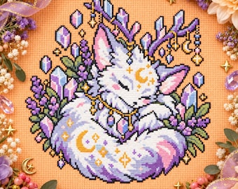 Può includere: Un ricamo a punto croce su tessuto color pesca raffigurante una volpe bianca addormentata con pelo dalle punte viola, corna e una mezzaluna sulla fronte. La volpe è circondata da rametti di lavanda viola, cristalli azzurri e stelle dorate.