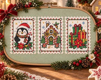 Può includere: Un telaio da ricamo ovale in legno contenente un tessuto verde chiaro con tre disegni rettangolari a punto croce. I disegni raffigurano un pinguino con cappello da Babbo Natale, una casa di pan di zenzero e regali, incorniciati da rami di pino.