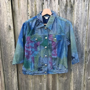 May include: A blue denim jacket with a floral print. The jacket has a button-up front and long sleeves.