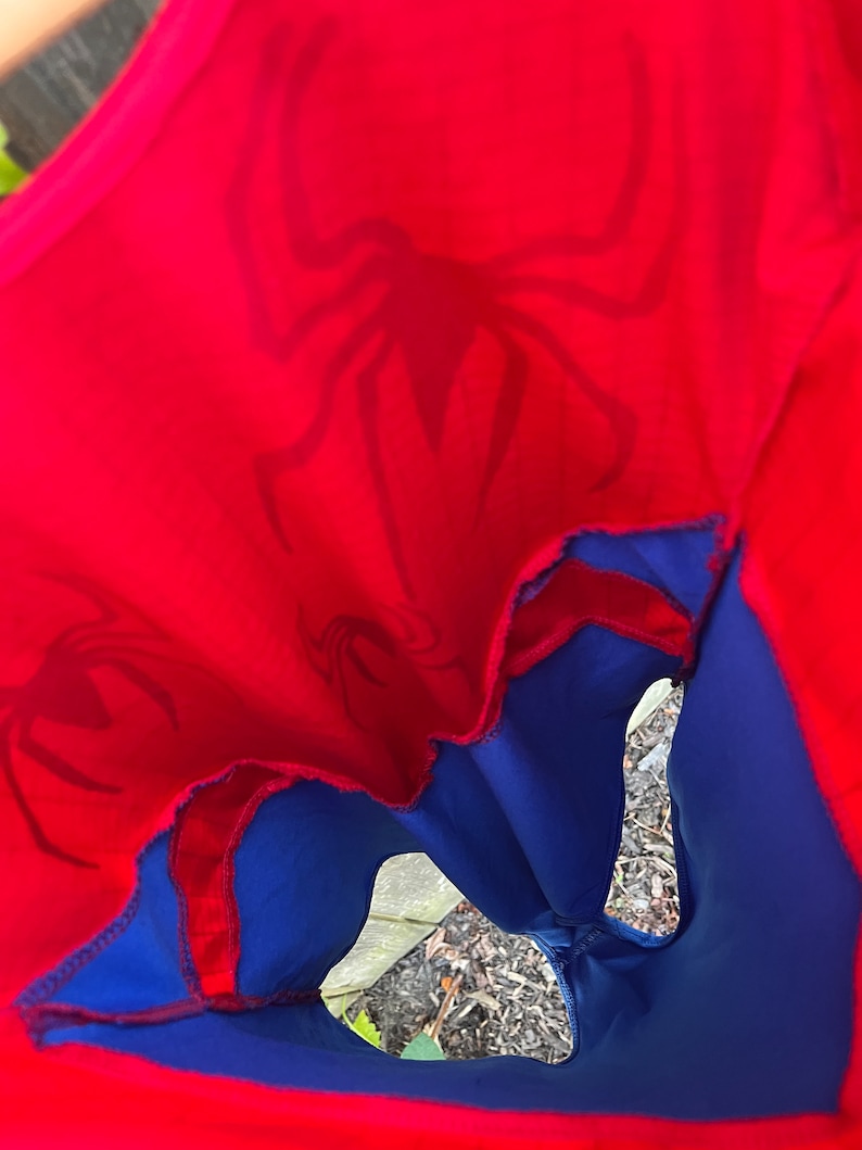 Pu&ograve; includere: Un costume da supereroe rosso e blu con un logo a forma di ragno. Il costume &egrave; realizzato in tessuto elastico e ha una cerniera sul retro.