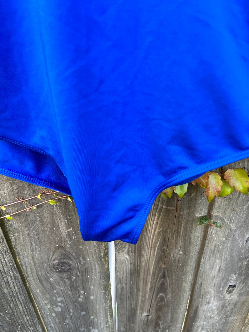 Pu&ograve; includere: Un costume da bagno blu brillante con un design semplice. Il costume da bagno &egrave; realizzato in un tessuto liscio ed elastico.