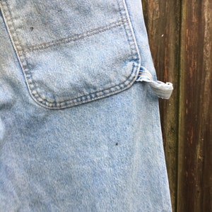 May include: A pair of light blue denim jeans with a brown leather belt loop and a large back pocket.