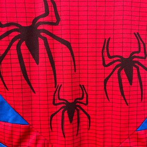 Pu&ograve; includere: Tessuto rosso con un motivo a ragnatela nera e tre sagome di ragni neri.