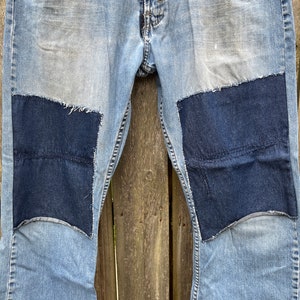 May include: A pair of blue denim jeans with two large dark blue denim patches sewn on the knees.