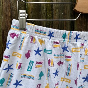 May include: White cotton pyjama shorts with a colourful fish and starfish print.