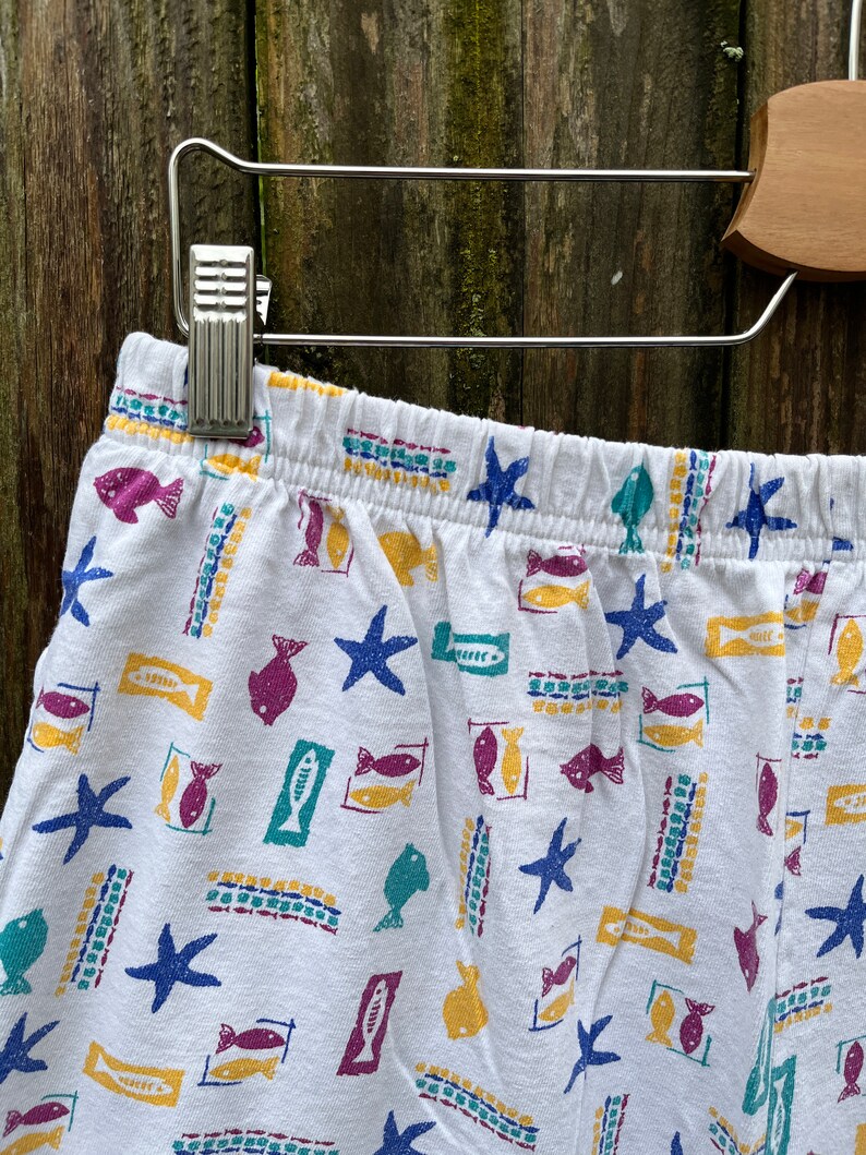 May include: White cotton pyjama shorts with a colourful fish and starfish print.