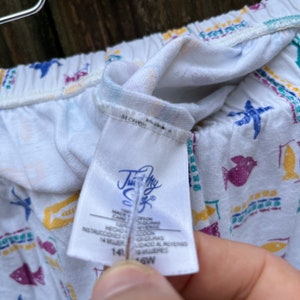 May include: White pyjama bottoms with a colourful fish and star pattern. The tag reads "Just My Size" and "14/16W".