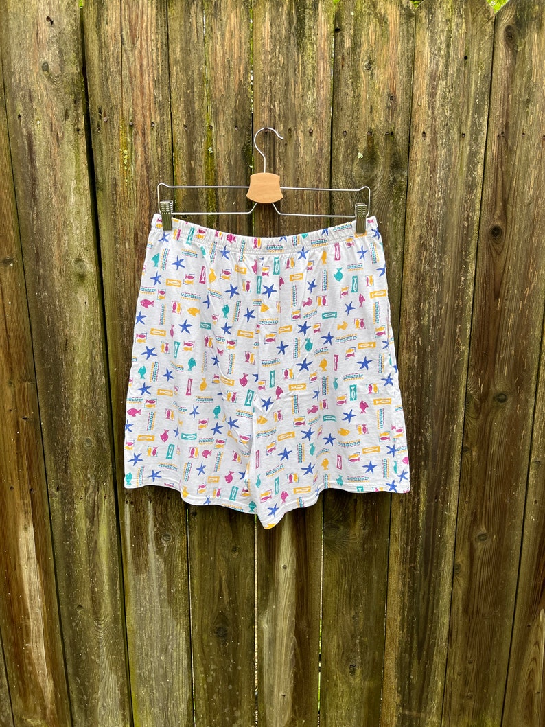 May include: White cotton shorts with a colourful pattern of fish, seashells, and starfish.