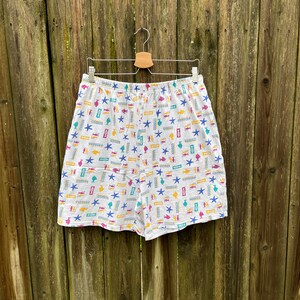 May include: White cotton shorts with a colourful print of fish, starfish, and other nautical designs.