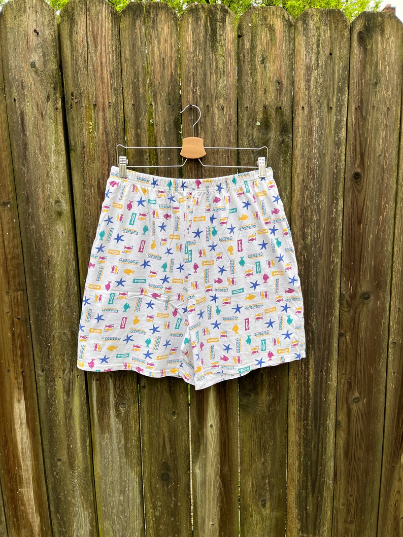 May include: White cotton shorts with a colourful print of fish, starfish, and other nautical designs.
