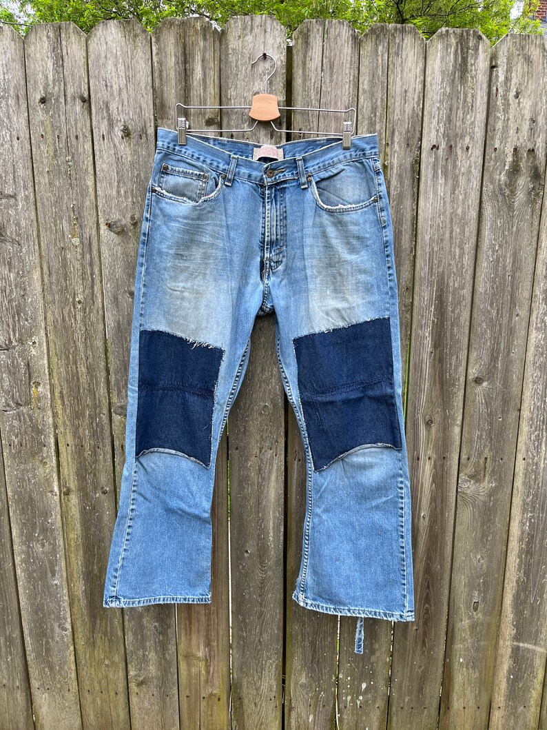 May include: A pair of blue denim bell bottom jeans with dark blue denim patches on the knees.