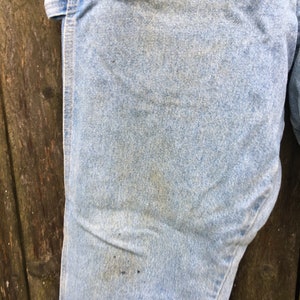 May include: Light blue denim jeans with a single seam down the side. The jeans have a worn look with some fading and discoloration.