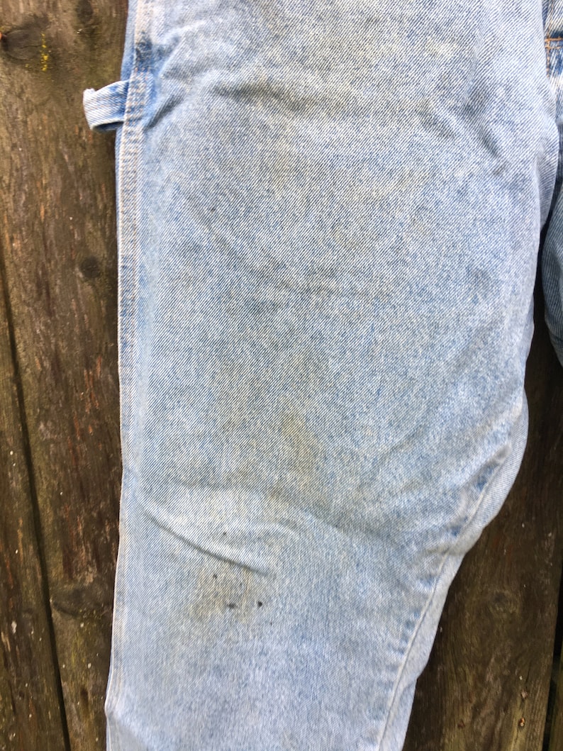 May include: Light blue denim jeans with a single seam down the side. The jeans have a worn look with some fading and discoloration.