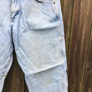 May include: Light blue denim carpenter jeans with a single rivet on the right pocket.