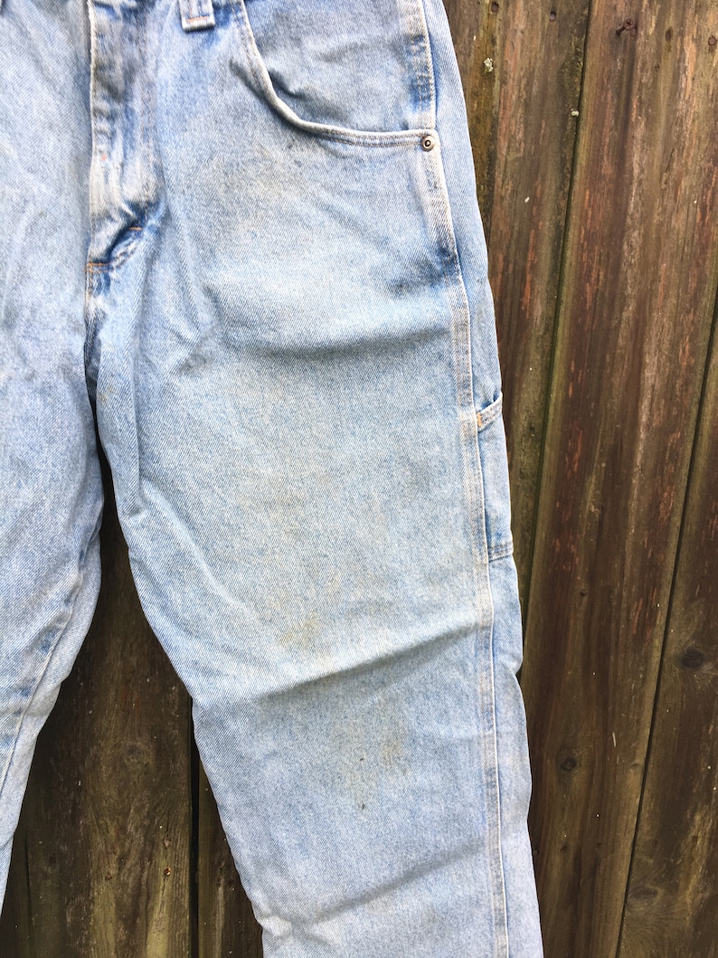 May include: Light blue denim carpenter jeans with a single rivet on the right pocket.