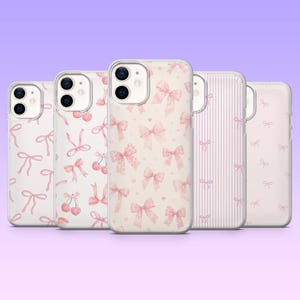 May include: Five clear smartphone cases arranged in a row, each featuring distinct light pink patterns. Designs include various sizes of tied bows, small cherries with stems, and vertical pinstripes, all set against a soft, pale background.