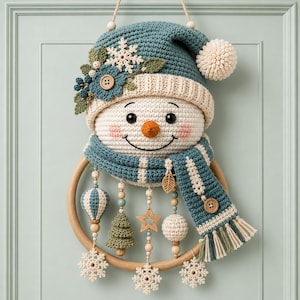May include: A crocheted snowman wall hanging featuring a teal hat with a white pom-pom, a matching teal scarf, and a wooden ring base. The snowman is decorated with a white snowflake, a teal flower, and wooden buttons. Dangling ornaments include crocheted trees, stars, spheres, and snowflakes.