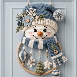 May include: A crocheted snowman wall hanging featuring a blue and cream striped hat with a pom-pom, a matching scarf, and a round wooden frame. The snowman is decorated with a crocheted flower, snowflake, and dangling ornaments including a star, tree, and spheres.