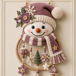 May include: A crocheted snowman wall hanging featuring a mauve hat with a white pom-pom, a striped mauve and white scarf, and a wooden hoop base. Dangling from the hoop are crocheted ornaments including snowflakes, a green tree, and a bell.