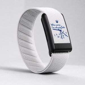 May include: A digital watch with a black rectangular face and a white textured elastic band. The watch face displays a blue crown icon, the text "Who cares I'm already late," and blue clock hands pointing to scattered, non-sequential numbers.