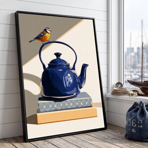 Può includere: Una stampa artistica da parete incorniciata raffigurante una teiera blu scuro lucida appoggiata su due libri impilati. Un piccolo uccellino blu e giallo è appollaiato sul manico della teiera. Lo sfondo presenta forme geometriche beige e marrone chiaro.