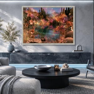 May include: A rectangular wall art print featuring a vibrant desert landscape with tall cacti, colorful wildflowers, and a reflective pool of water under a glowing, multi-colored sky, all encased in a light-colored wooden frame.