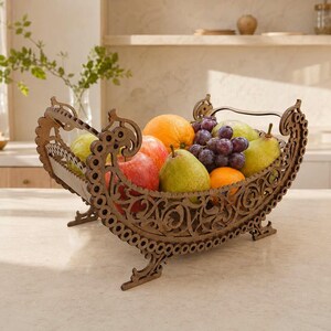 May include: A brown, laser-cut wooden fruit bowl with an intricate, ornate scrollwork pattern and curved, elevated ends. The bowl is filled with a variety of fresh fruit, including red apples, green pears, oranges, and a cluster of purple grapes.