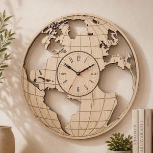 Puede incluir: Un reloj de pared circular con un marco de madera clara en forma de mapa mundial con continentes y líneas de cuadrícula cortadas con láser. El centro contiene una esfera redonda con números arábigos negros, manecillas negras y un segundero rojo.