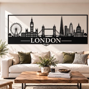 Op de afbeelding: Een rechthoekig wandkunstobject van zwart metaal met een gedetailleerd silhouet van de skyline van Londen, inclusief de London Eye, Big Ben en Tower Bridge. Het woord LONDON staat in witte hoofdletters onder het silhouet afgebeeld.