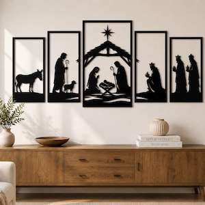 May include: A five-piece black metal wall art set depicting a nativity scene. The panels feature silhouettes of a donkey, a shepherd with a sheep, the holy family in a stable under a star, and the three wise men, all rendered in a flat, cutout style.