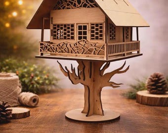 Puede incluir: Un modelo de madera cortado con láser que representa una casa elevada sobre una base con forma de árbol. La estructura cuenta con un techo a dos aguas, un balcón con barandillas intrincadas y paredes con ventanas de rejilla y una puerta.