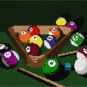 May include: A cross-stitch embroidery pattern depicting a game of billiards. The design features a wooden triangle rack containing colorful numbered balls, with additional scattered balls and two wooden cues on a dark green felt surface.