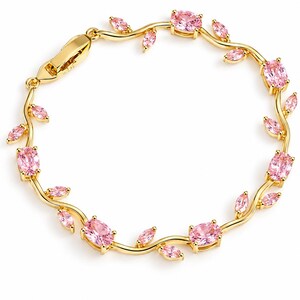 May include: A gold-tone bracelet featuring a vine-like design with alternating oval and marquise-cut pink gemstones. The metal band curves to mimic natural stems, accented by small pink stones and a secure clasp closure on one end.