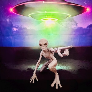 Puede incluir: Una figura alienígena de piel clara y cuerpo esbelto en posición agachada con un brazo extendido hacia adelante. Sobre la figura, un OVNI metálico en forma de disco brilla con luces rosas y verdes contra un cielo estrellado violeta.
