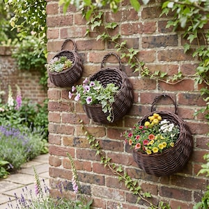 May include: Three round, dark brown woven wicker wall baskets with arched handles, each mounted on a brick wall. The baskets contain various potted plants, including green succulents, purple flowers with green foliage, and yellow and white flowers.