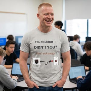 Puede incluir: Una camiseta de manga corta de color gris claro con el texto en negro "YOU TOUCHED IT. DIDN'T YOU?" seguido de "That's technology." en letra cursiva marrón. Debajo del texto hay un gráfico de un dial y un botón conectados por un cable negro.