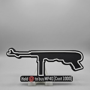 Può includere: Una sagoma in bianco e nero di un mitra MP40 con una superficie testurizzata. Sotto l'arma si trova un cartello rettangolare con il testo "Hold [icona quadrata] to buy MP40 [Cost 1000]" con un'icona quadrata rossa e scritte bianche.