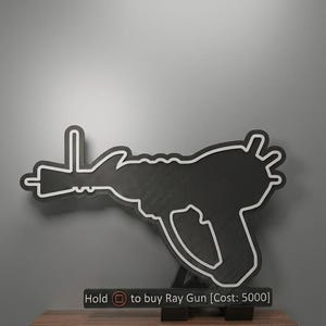 May include: A black silhouette of a ray gun with a white outline, mounted on a stand. Below the gun, a rectangular sign features the text: Hold [square icon] to buy Ray Gun [Cost: 5000]. The design mimics a video game interface element.