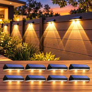 May include: A set of eight rectangular solar-powered wall lights with black housings and blue solar panels. Each light features two downward-facing bulbs that emit a warm yellow glow, shown mounted on a wooden fence and on a wooden surface.