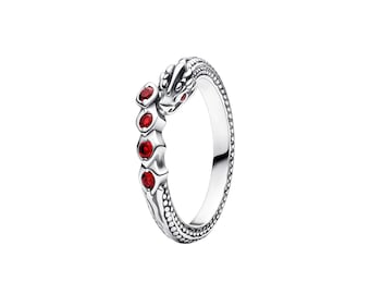 May include: A silver ring shaped like a coiled snake with a textured scale pattern along the band. The head of the snake features a small red stone eye, and the body is accented with four round, vibrant red stones set in a vertical row.