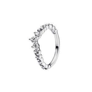 May include: A silver-toned ring featuring a V-shaped chevron design with three clear round-cut stones set at the peak. The band is crafted with intricate scrollwork and filigree patterns extending along the sides of the metal shank.