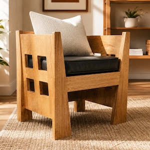 May include: A light brown wooden armchair featuring a geometric cutout design on the side panels, a black seat cushion, and a textured off-white throw pillow. The chair has a sturdy frame with wide legs and a low backrest structure.