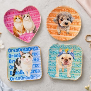 May include: Four ceramic trinket dishes with gold-toned rims. One heart-shaped dish features two cats and the text "Luna & Oliver". One round dish features a dog and the text "Charlie". Two square dishes feature a cat and a dog with the text "Oreo" and "Bella".