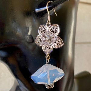 May include: Silver filigree flower dangle earrings with a clear faceted crystal drop.