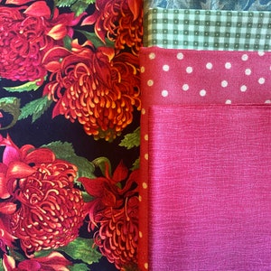 May include: A collection of fabric swatches featuring a variety of patterns and colors. The swatches include a floral print, a green gingham pattern, a red polka dot pattern, and a solid pink fabric.