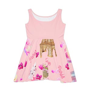 May include: A light pink sleeveless dress featuring a repeating print of the Eiffel Tower, pink hearts, bows, and baskets of flowers. The word Paris is written in a cursive pink font across the skirt, which has a flared, A-line silhouette.